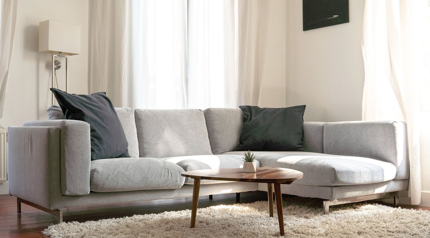 Living room with a grey couch, pillows, and rug at Savannah Oaks 1 bedroom apartments in San Antonio.