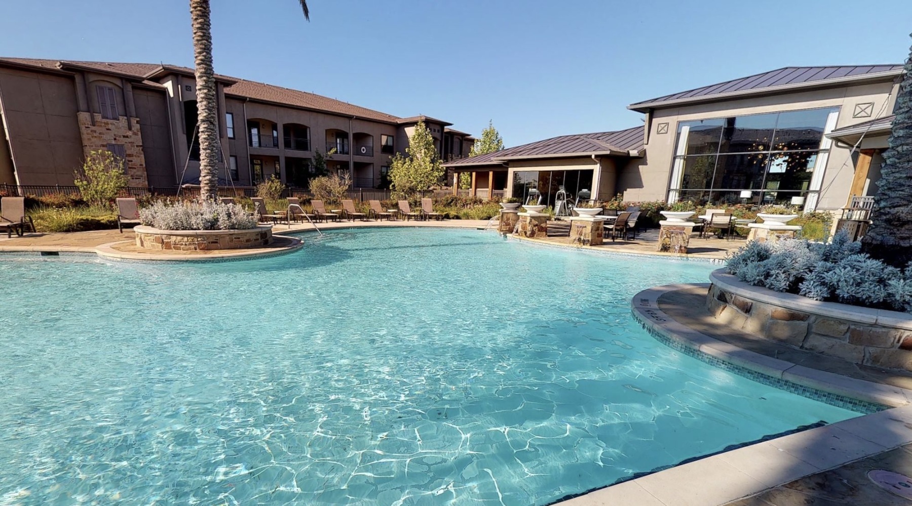 resort style pool with seating with a building behind it